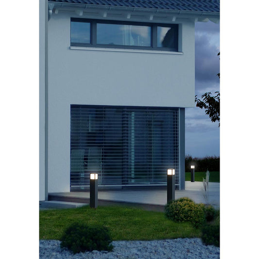 Drei schwarze Wegeleuchten mit quadratischem Leuchtenkopf vor einem modernen Einfamilienhaus im Abendlicht.